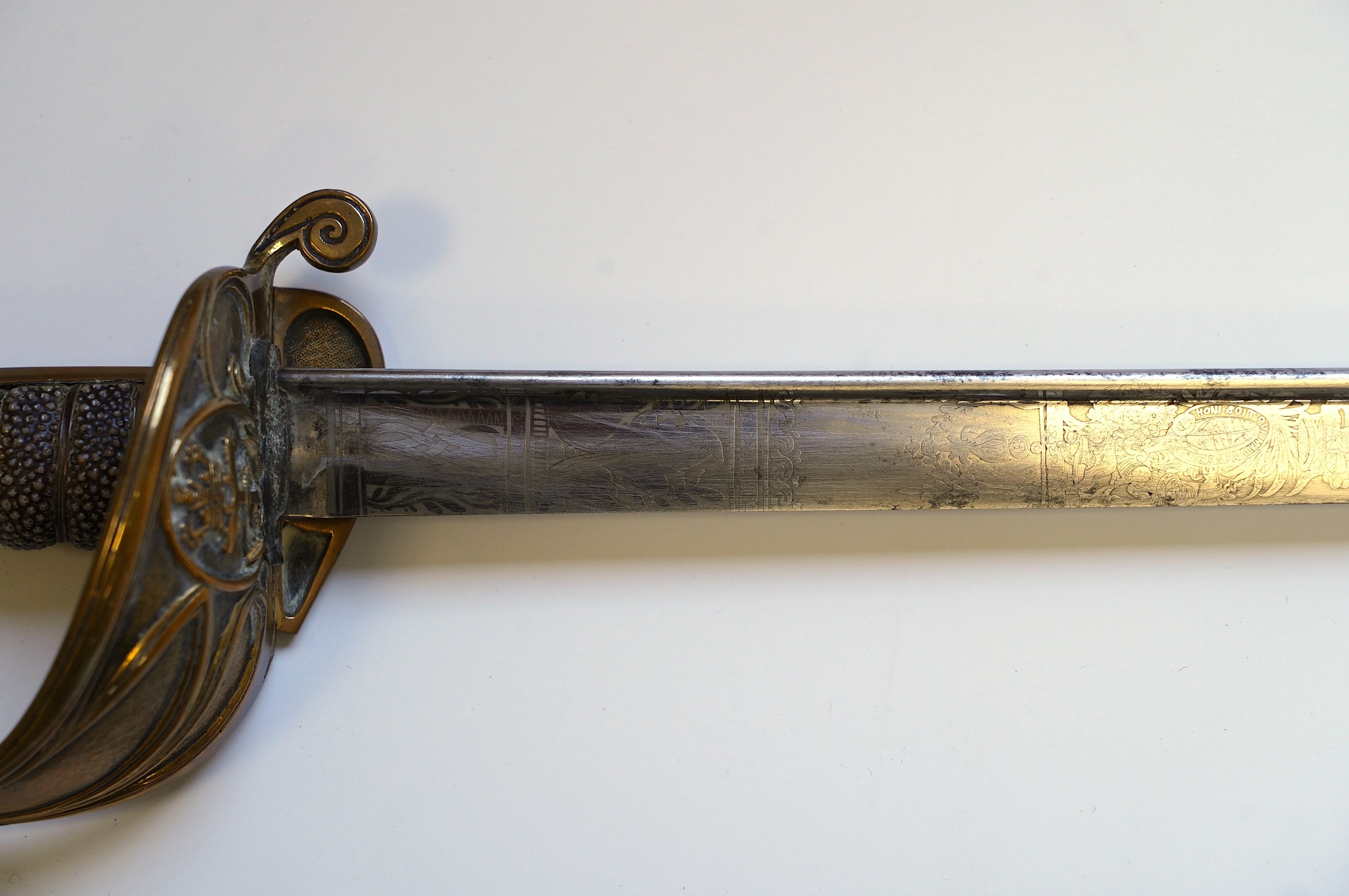 An early 19th century Royal Navy officer's sword with engraved blade, folding knuckle guard, lion’s head pommel and shagreen grip, leather scabbard with brass fittings, blade 73.5cm. Condition - fair, some wear overall.